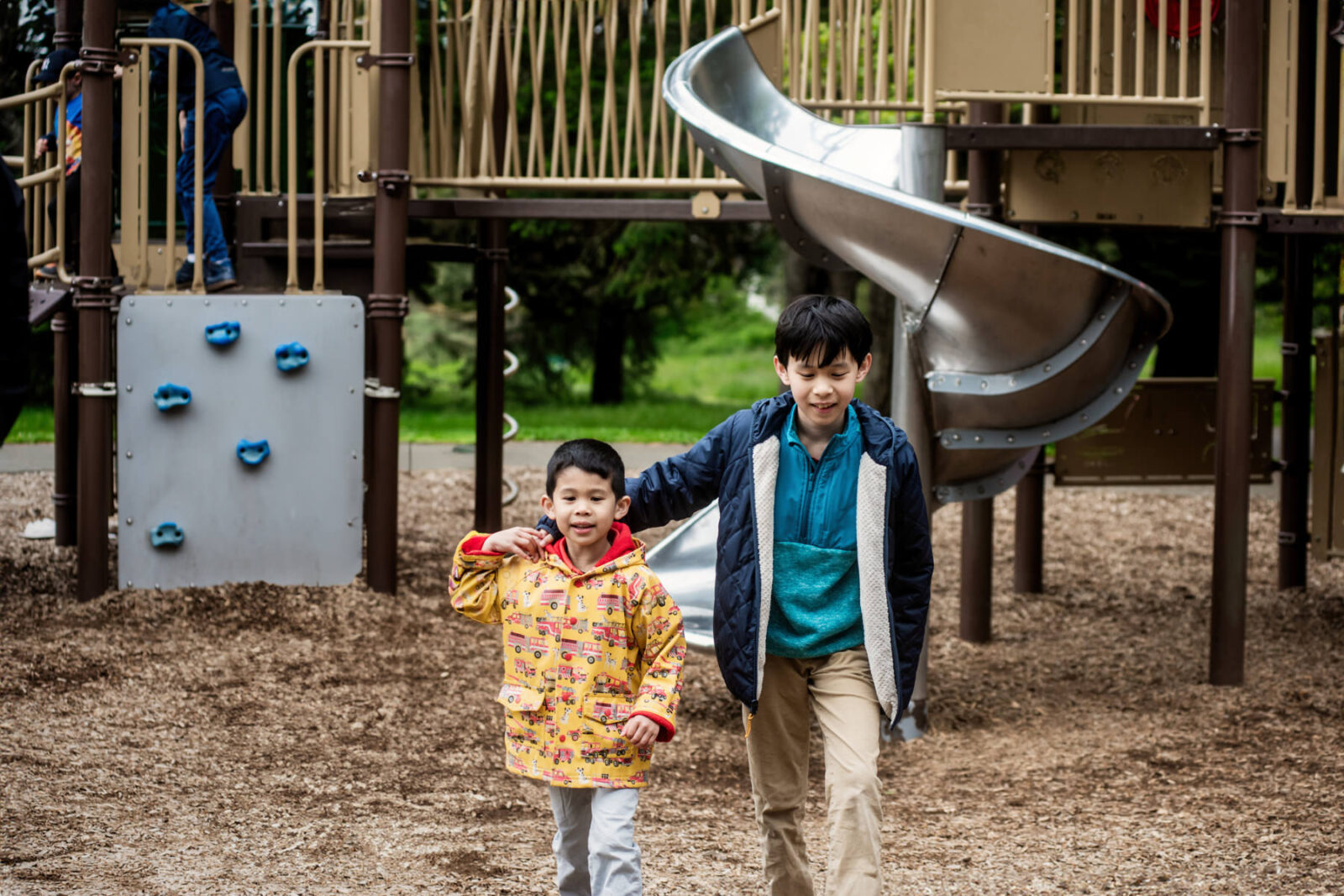 Two brothers are in front of the slides at the Beacon Hill Park play area in Victoria BC