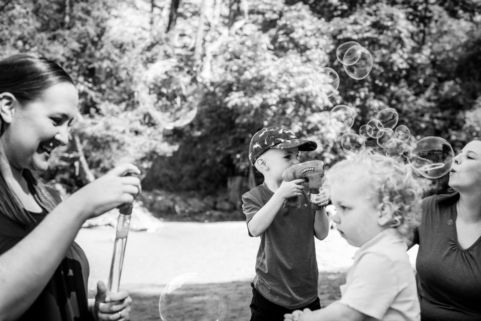 Documentary family photos in black and white of two boys playing with bubbles on the beach in Victoria BC