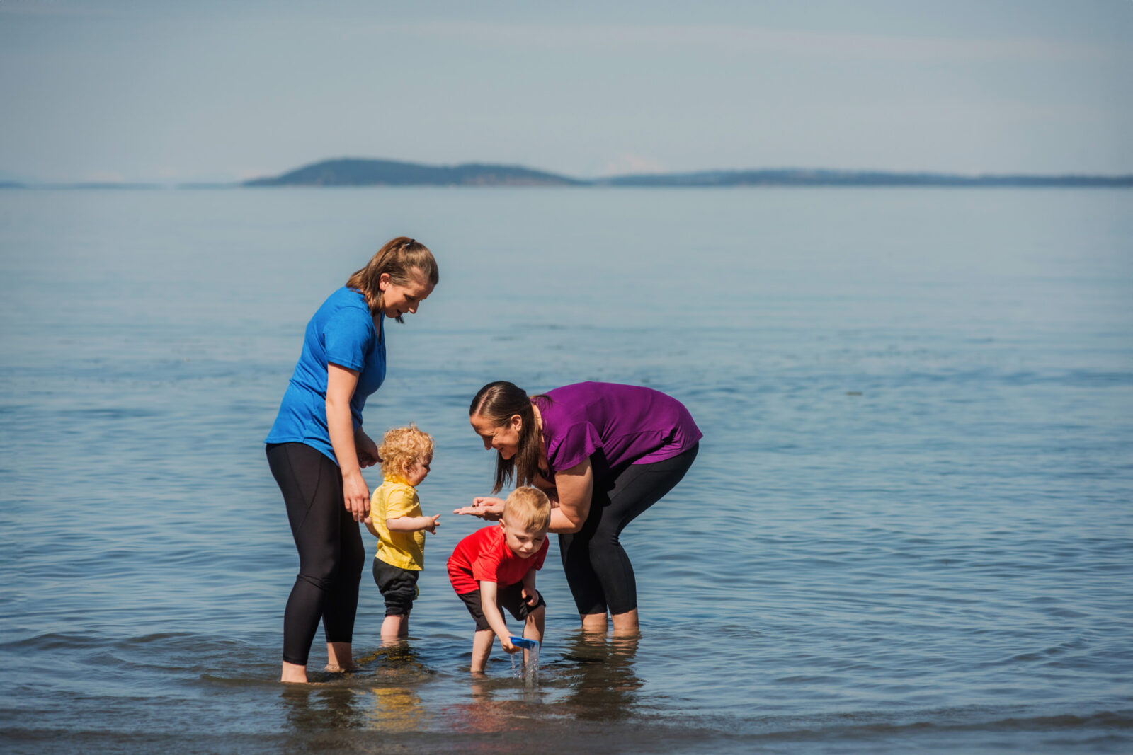 A colorful candid photo of a family playing at low tide on the beach in Victoria BC.