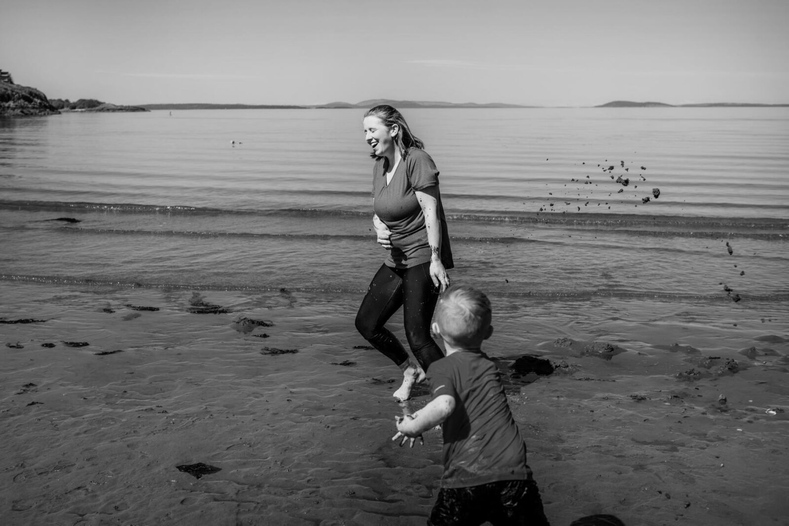 A boy throws some mud at his mom on the beach in Victoria BC