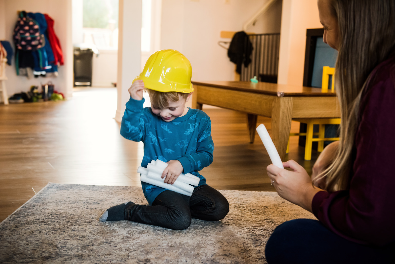 A photo of a toddler in his living room wearing a firefighter's hat.