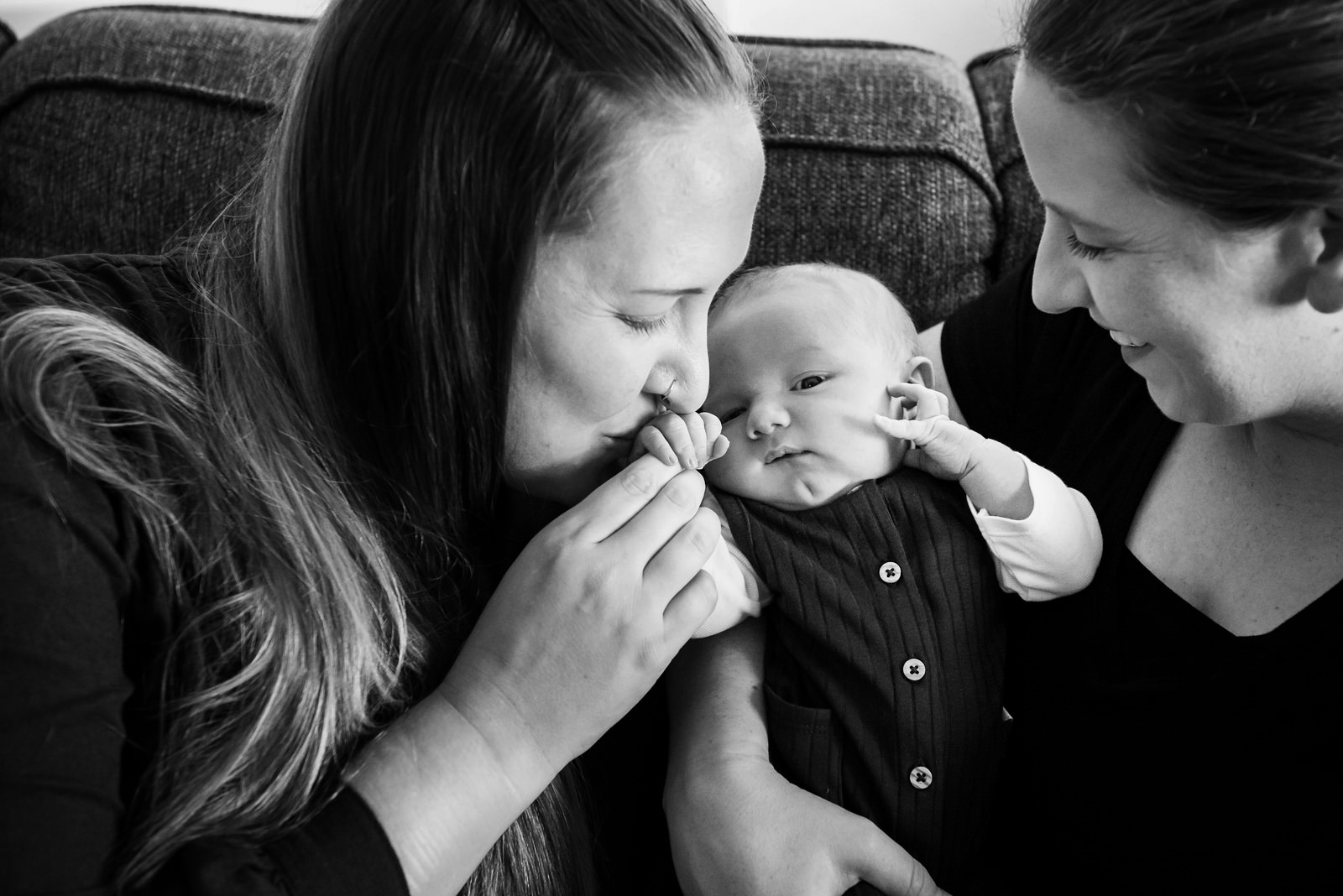 Mom kissing her newborn baby's hands.