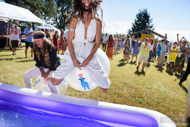 A fun and funny wedding photo of a couple doing a race on bouncy balls. The bride is up in the air and you can see a huge smile on her face as she beats the groom to the finish line.